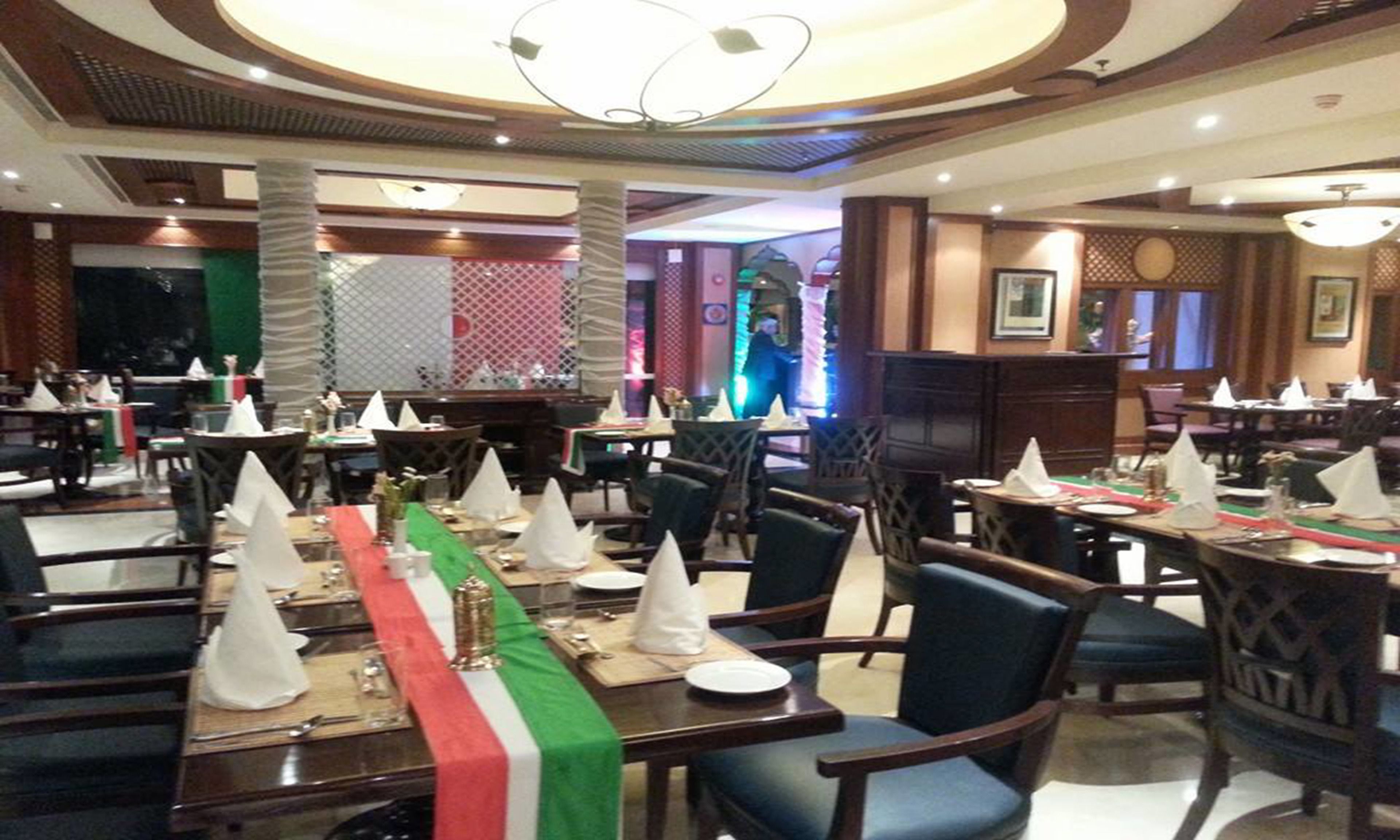 A restaurant with multiple dining tables set with white napkins and a green table runner.