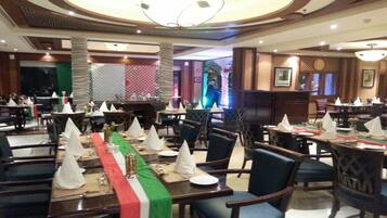 A restaurant with multiple dining tables set with white napkins and a green table runner.