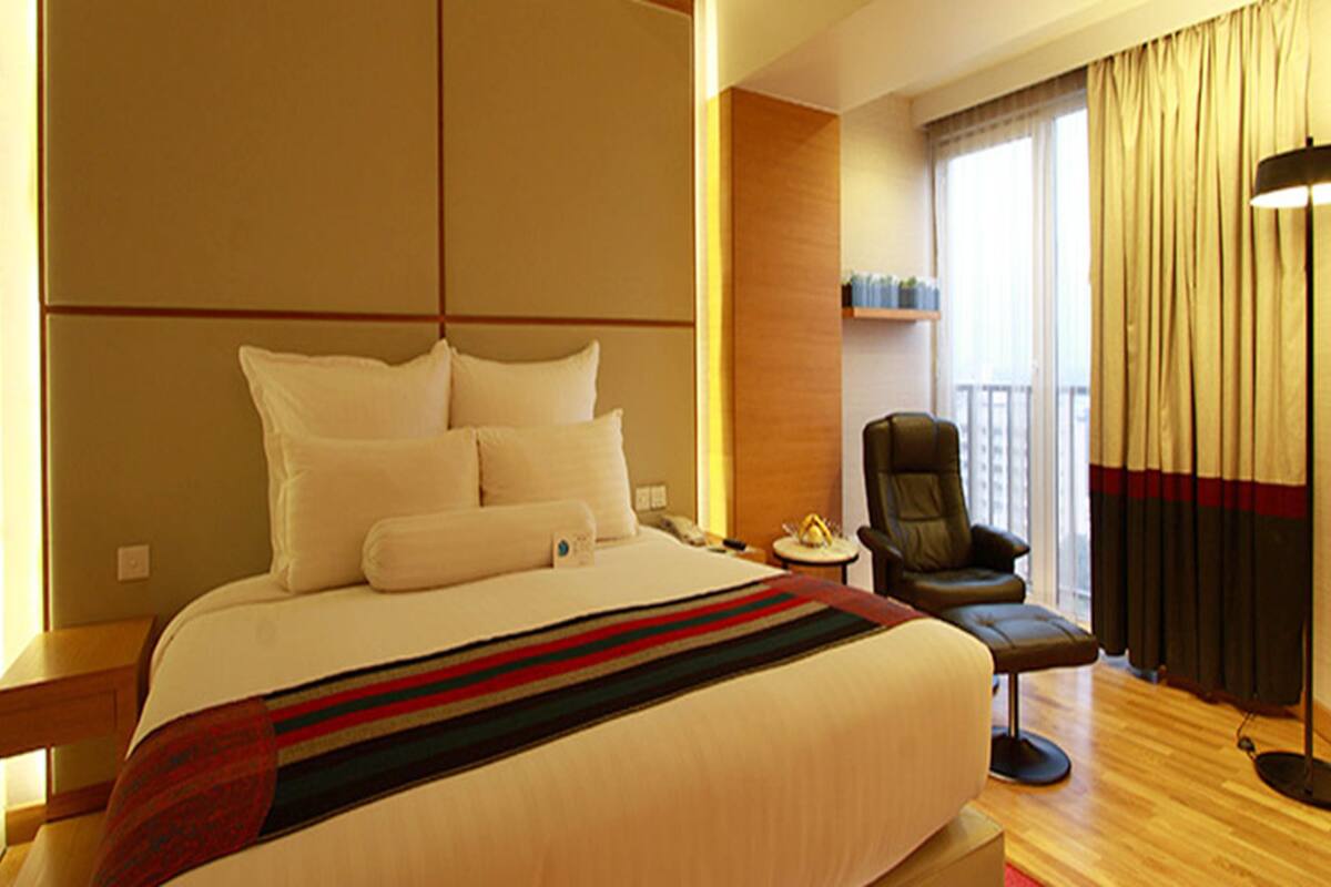 Ein Hotelzimmer mit einem großen Bett, einem Schreibtisch, einem Sessel und einer Stehlampe.