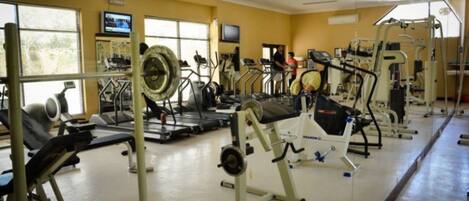 Une salle de sport équipée de divers appareils d’exercice, notamment des tapis de course et des appareils de musculation.