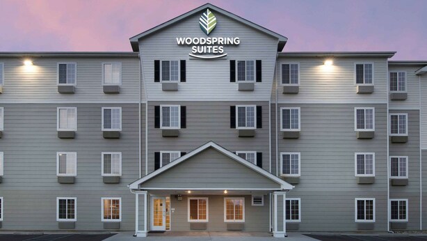 Un hôtel à plusieurs étages, avec une enseigne indiquant « Woodspring Suites » à l’entrée.