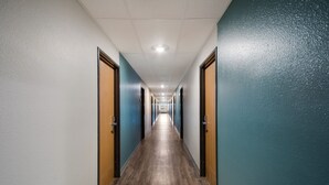 Un long couloir étroit, doté d’un plancher en bois et de portes des deux côtés.