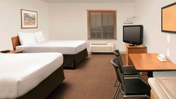 A hotel room with two beds, a desk with a chair, a television, and a window with blinds.