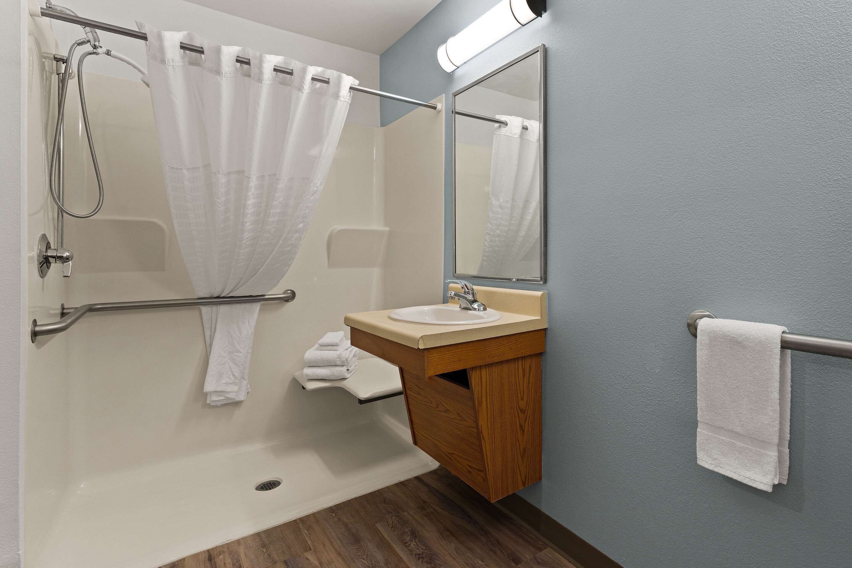 A bathroom with a shower, a sink, a mirror, and a towel rack.