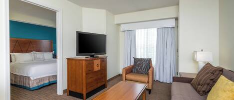 A hotel room with a bed, a television on a wooden dresser, a sofa, and a small table.