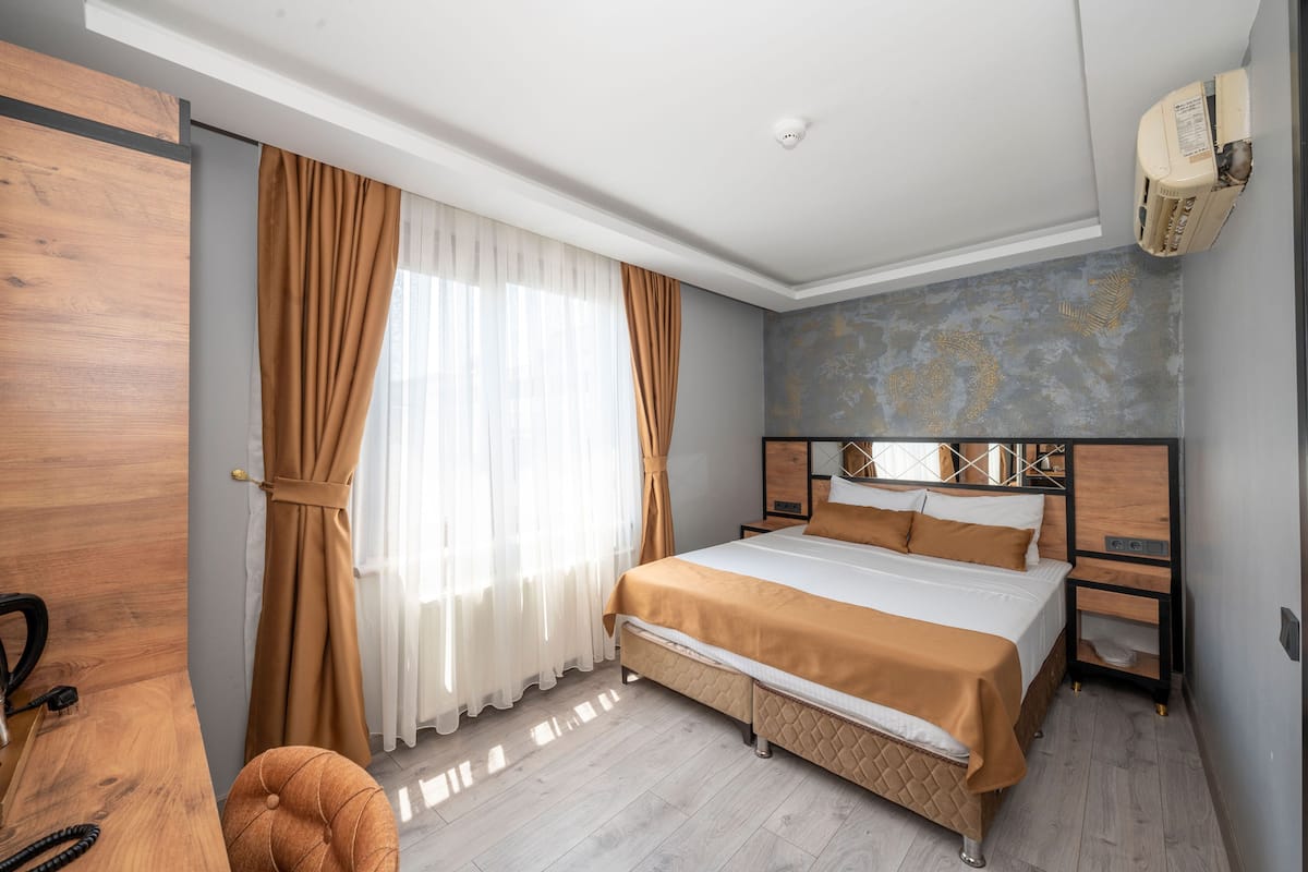 Una habitación de hotel con una cama, un armario de madera, una mesita de noche y un calentador de pared.