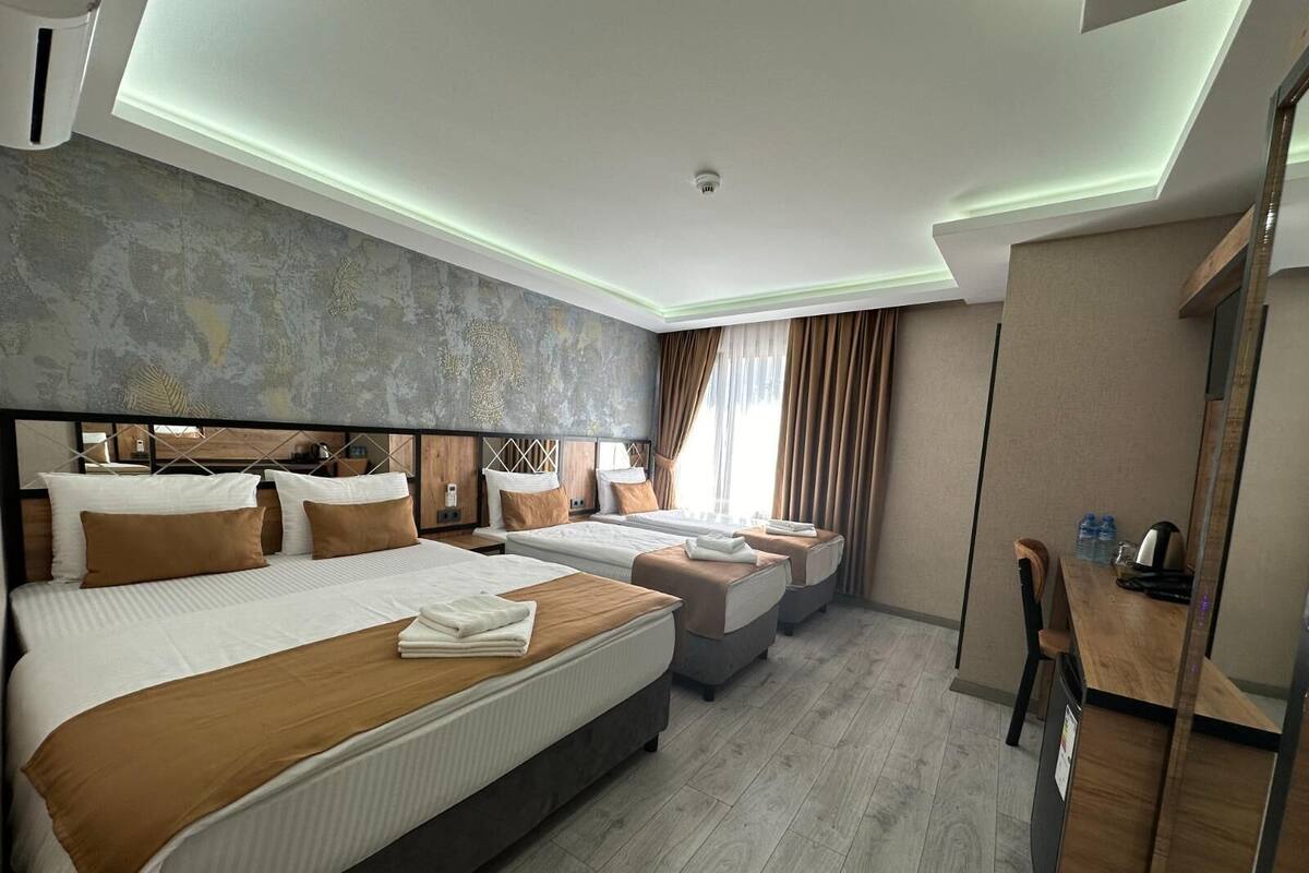 Una habitación de hotel moderna con una cama grande, dos camas más pequeñas, un escritorio y una silla.