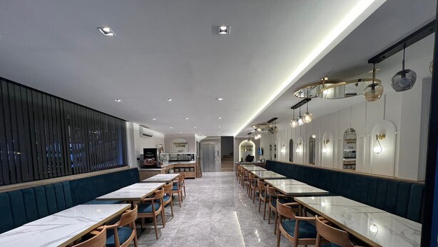 A modern restaurant with long communal tables and booths, a kitchen area, and a clean, contemporary design. - Boutique Dedem Hotel (Istanbul)