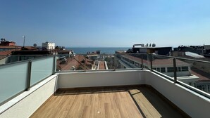A rooftop terrace with a wooden floor, glass balustrade, and a view of the sea and cityscape. - Boutique Dedem Hotel (Istanbul)
