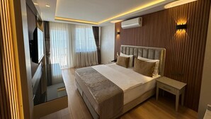 A modern hotel room with a large bed, a bedside table, a TV, and a view of the city. - Boutique Dedem Hotel (Istanbul)