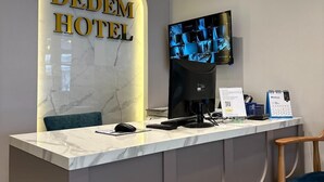 A hotel reception desk with a marble counter, a digital screen displaying a cityscape, and a sign reading "DEDEM HOTEL". - Boutique Dedem Hotel (Istanbul)
