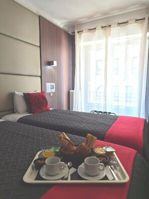 A hotel room with two beds, a tray with breakfast items, and a window with curtains. - Hotel Schtak (Cannes)