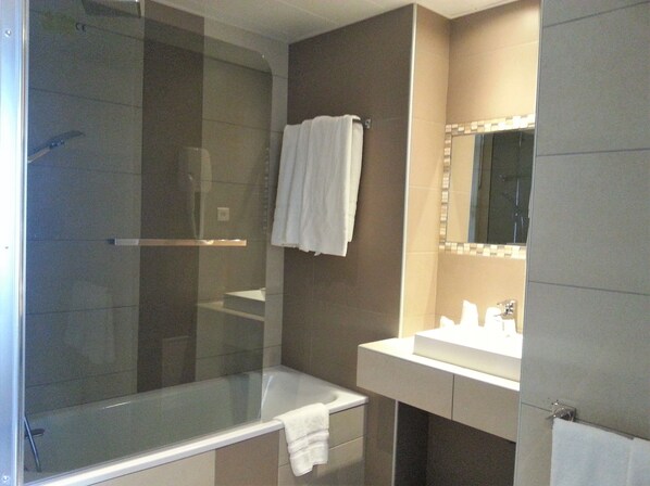 A modern bathroom with a glass-enclosed shower, a bathtub, and a vanity with a mirror.