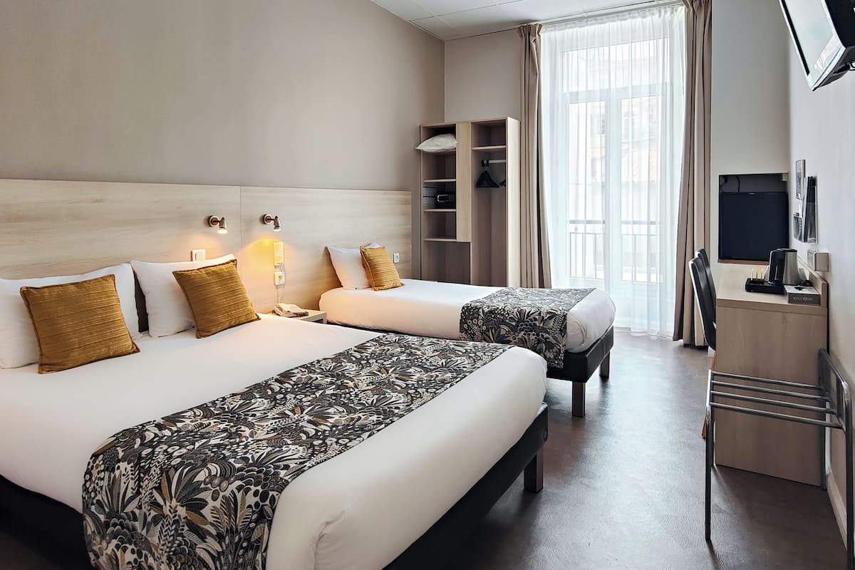 A hotel room with two beds, a wardrobe, a desk, a television, and a window with curtains.