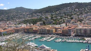 A marina with numerous boats docked, surrounded by densely packed buildings with varied architecture. - Hôtel Helvétique (Nice)
