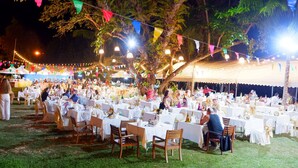 An outdoor event with multiple round tables covered with white tablecloths, surrounded by guests. - Supalai Scenic Bay Resort And Spa (Pa Klok)