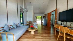 A spacious living area with a sofa, chairs, a coffee table, and a TV.