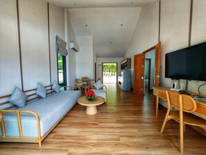 Un amplio salón con sofá, sillas, una mesa de centro y televisor.