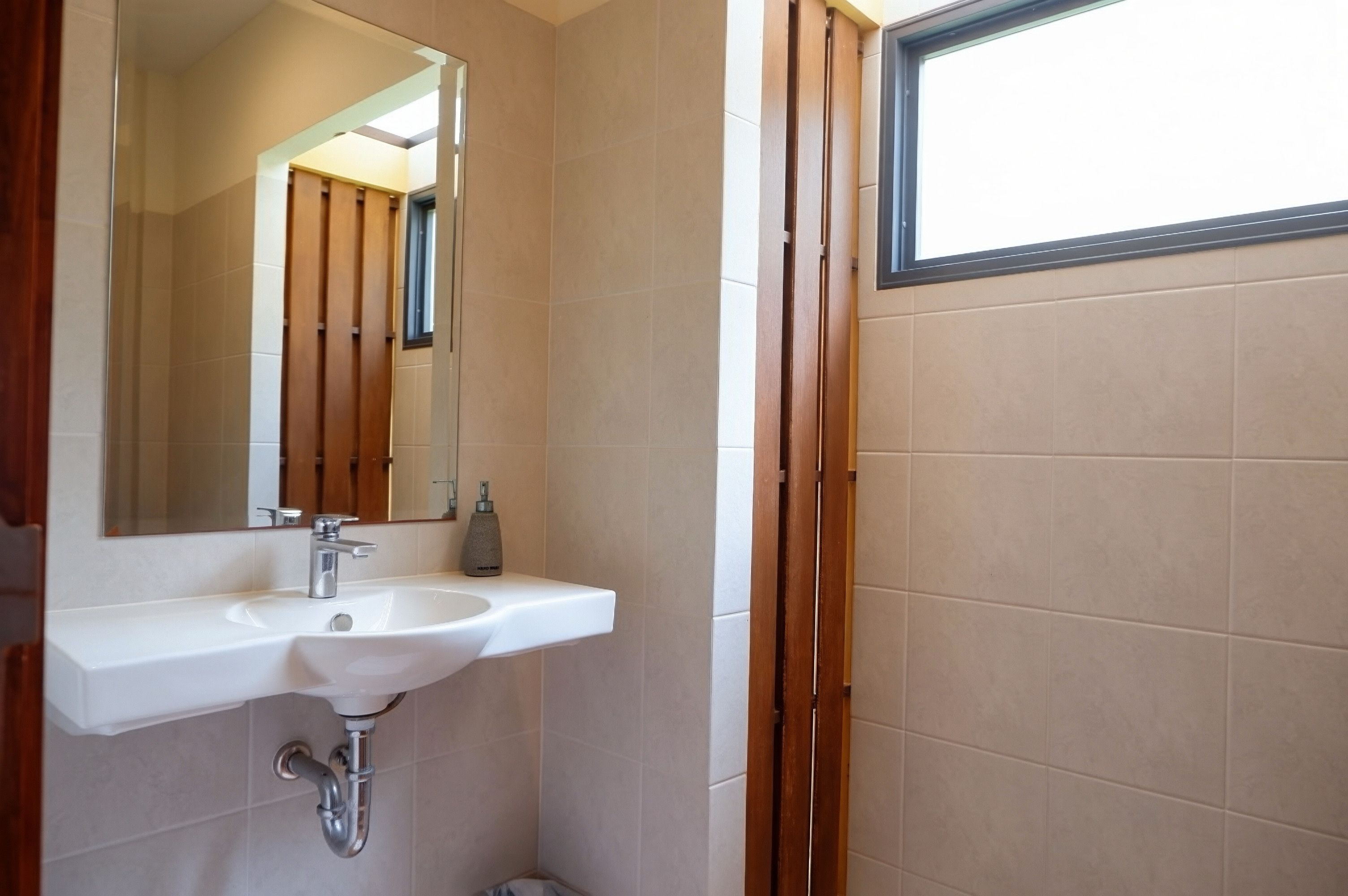 A bathroom with a white sink, a mirror, and a window.