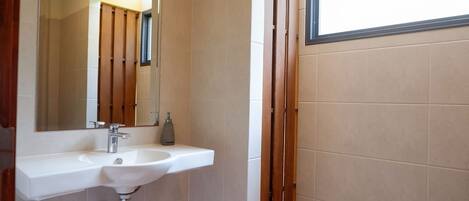 A bathroom with a white sink, a mirror, and a window.