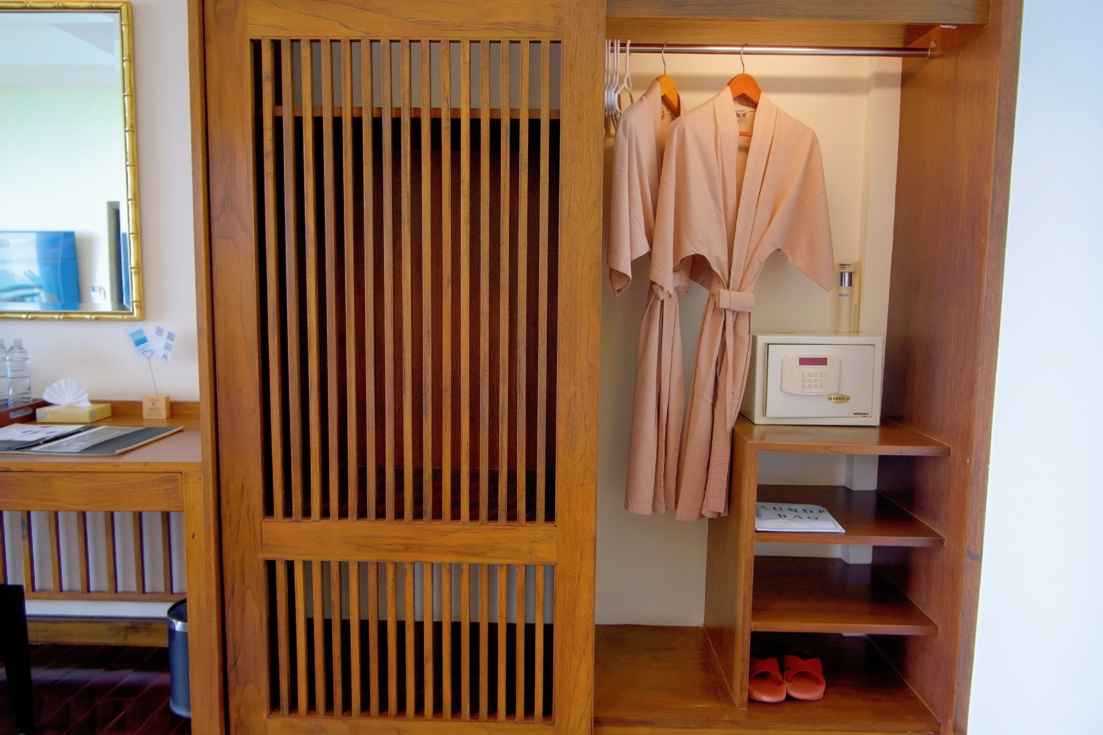 Un armario de madera con puerta espejada, una percha y un estante para zapatos y artículos de aseo.
