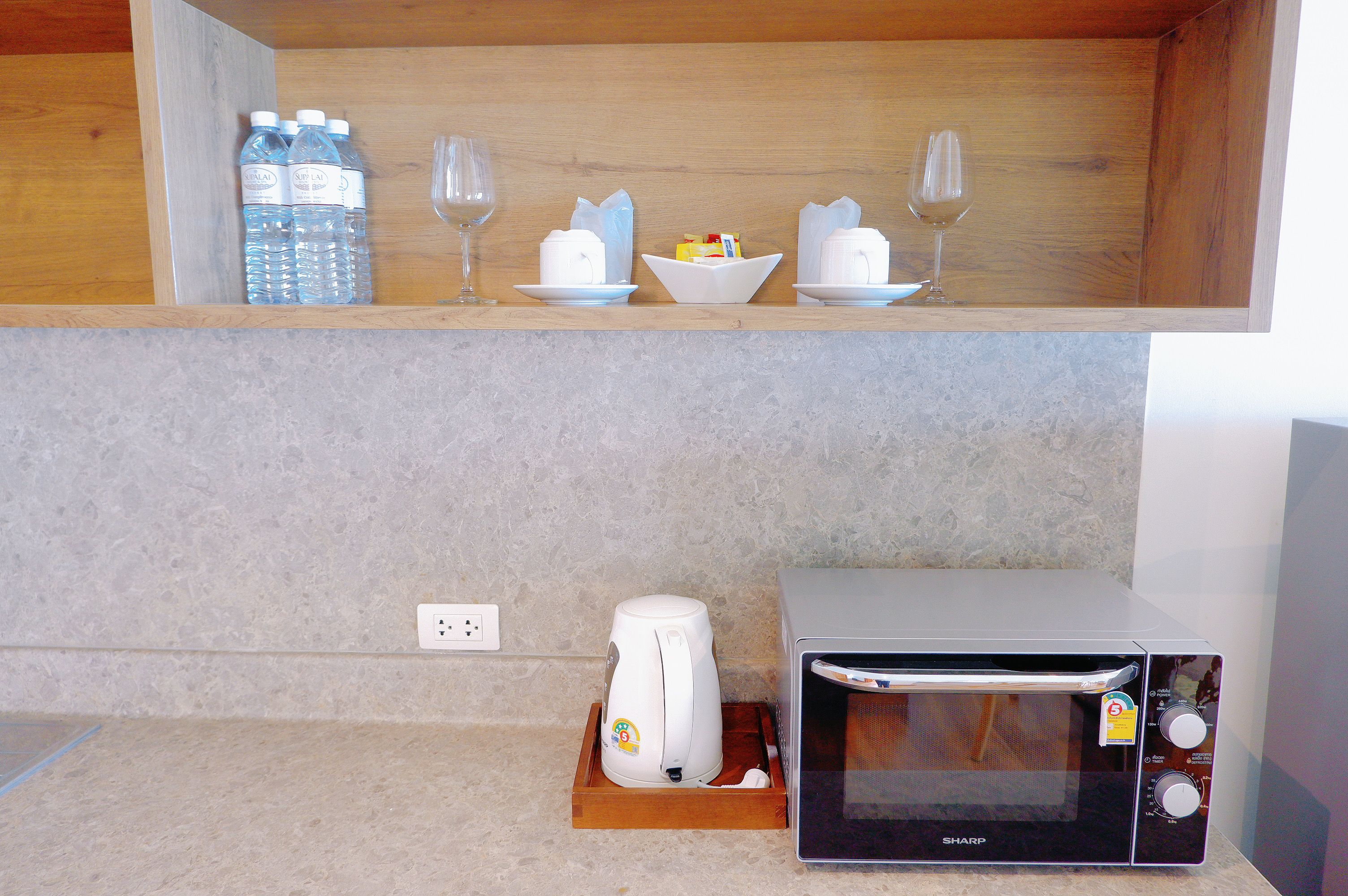 Una cocina con microondas, tostadora y encimera con una botella de agua y vasos.