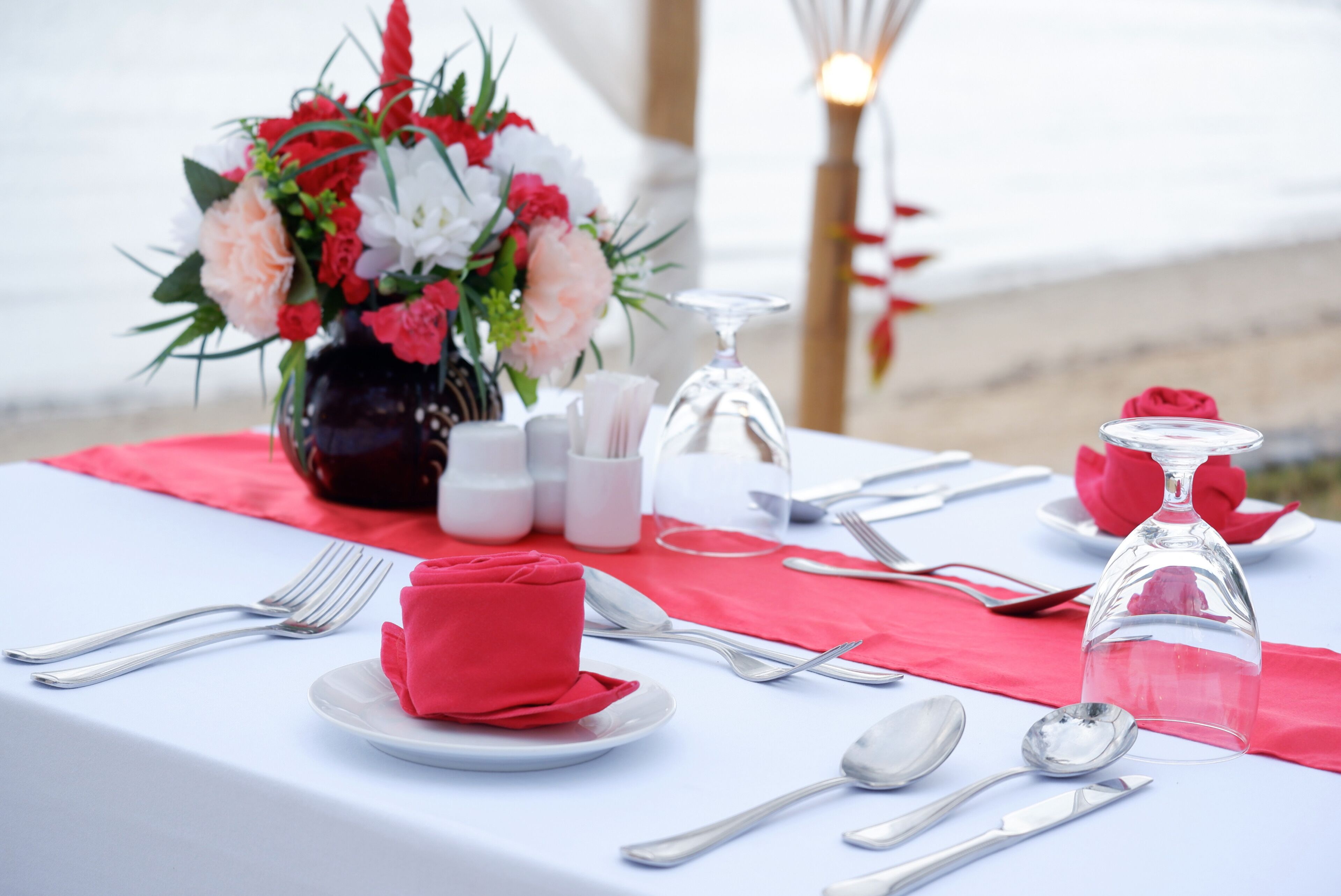 Una mesa dispuesta para una comida, con un florero, saleros y pimenteros, una copa de vino y cubiertos ordenados.
