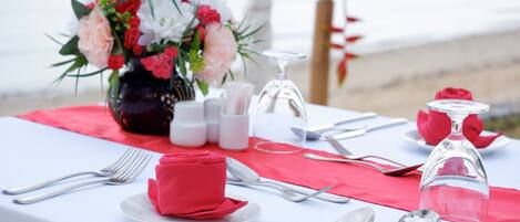 Una mesa dispuesta para una comida, con un florero, saleros y pimenteros, una copa de vino y cubiertos ordenados.