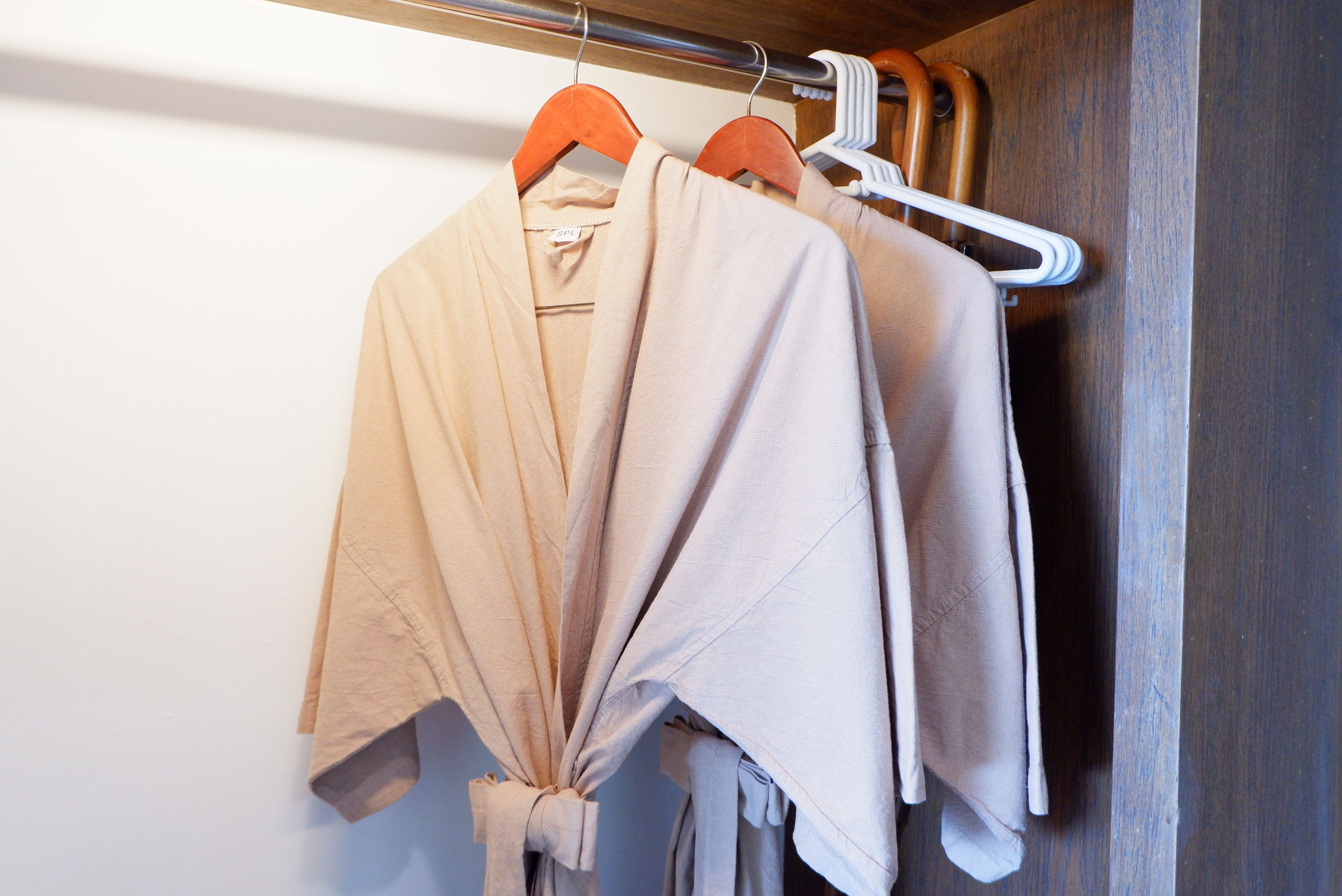 A wooden wardrobe with a hanging rod for clothes.