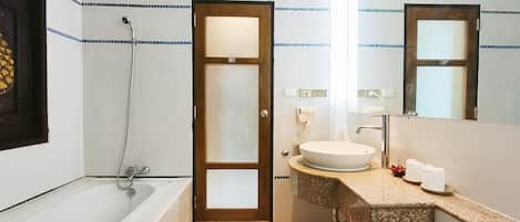 Un baño con una bañera, un lavabo con espejo y un perchero para toallas.