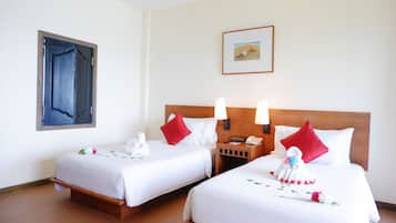 A hotel room with two beds, a wooden headboard, a nightstand with a phone, and a painting on the wall.