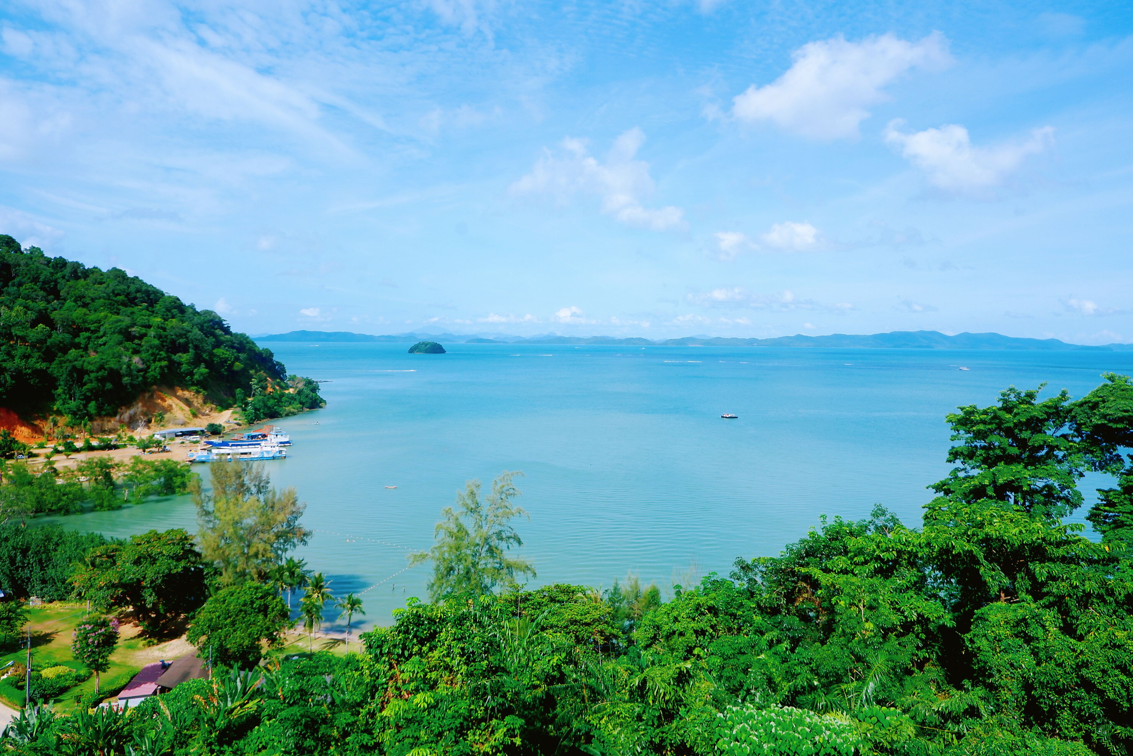A coastal landscape with a clear sky, a body of water, and a small island in the distance.
