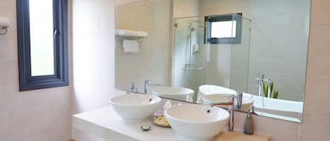 A modern bathroom with two sinks, a large mirror, and a shower.