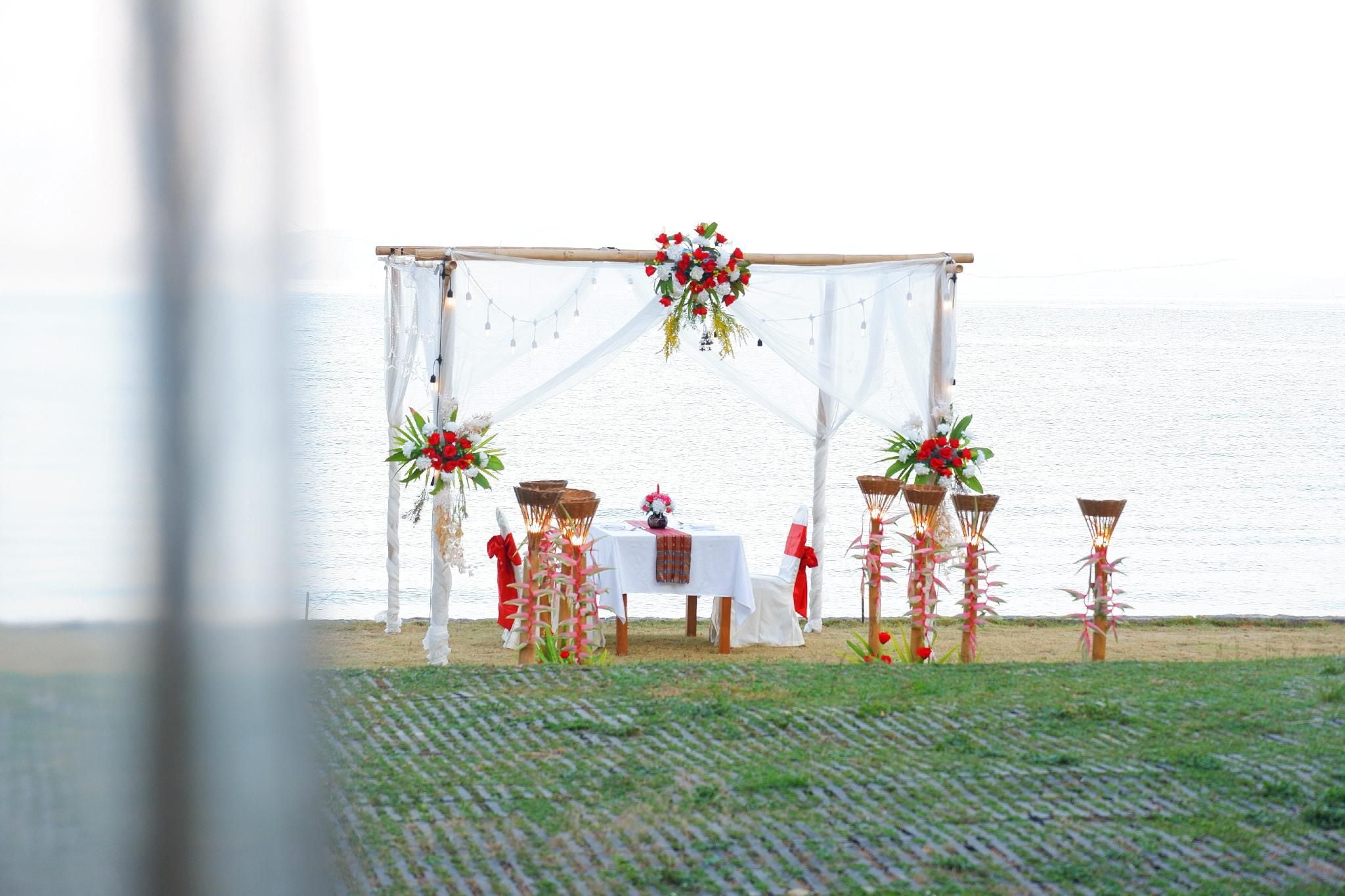 Decoración para boda al aire libre con toldo blanco, mesas, sillas y adornos florales.
