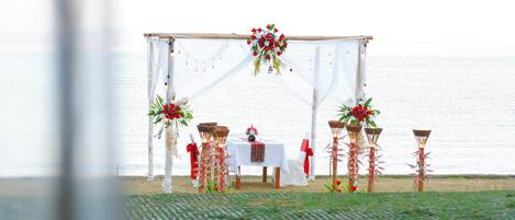 Decoración para boda al aire libre con toldo blanco, mesas, sillas y adornos florales.