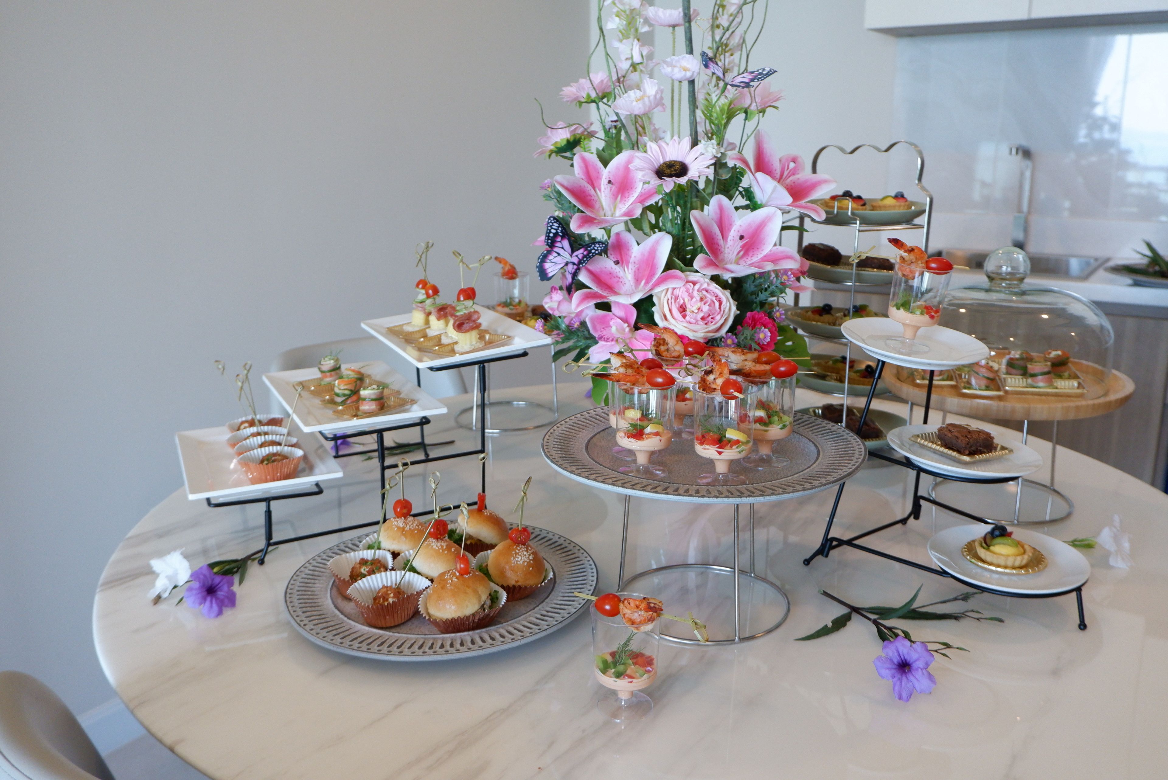 A round table with various food items and a floral centerpiece.
