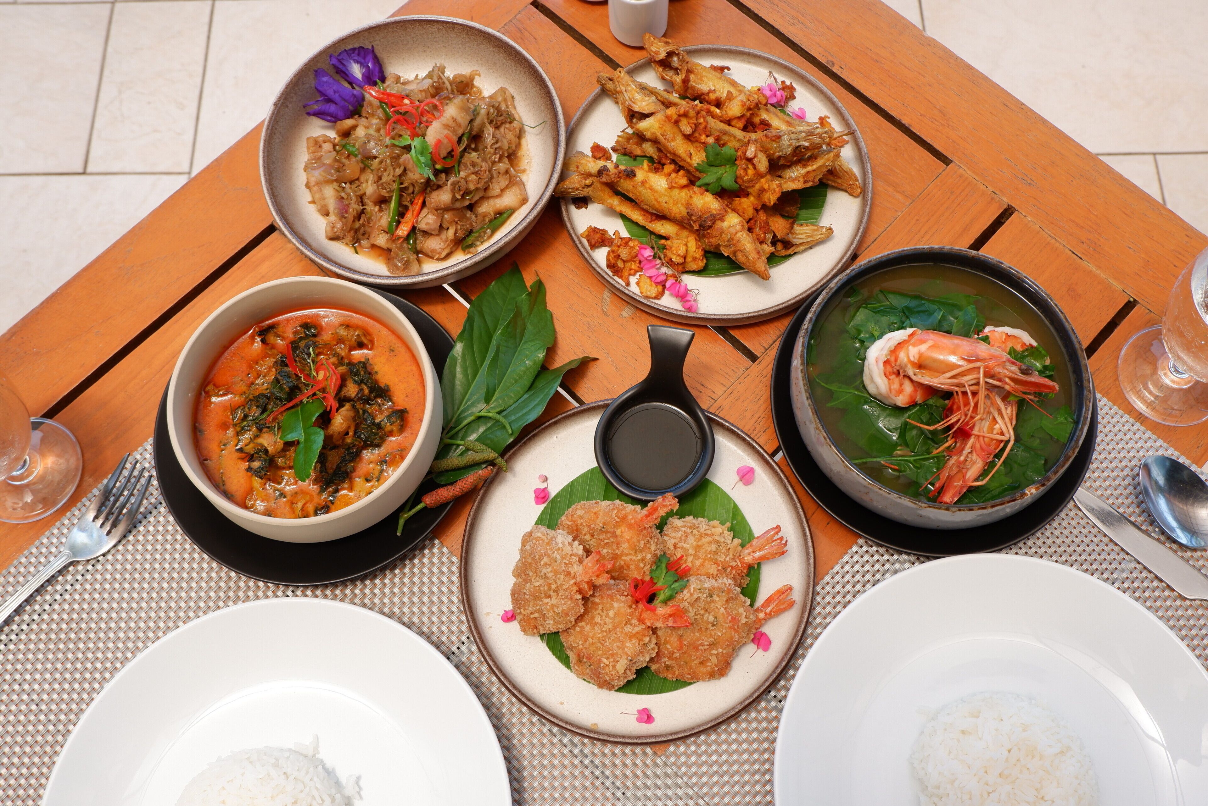 A table with various dishes, including seafood, rice, and a soup.