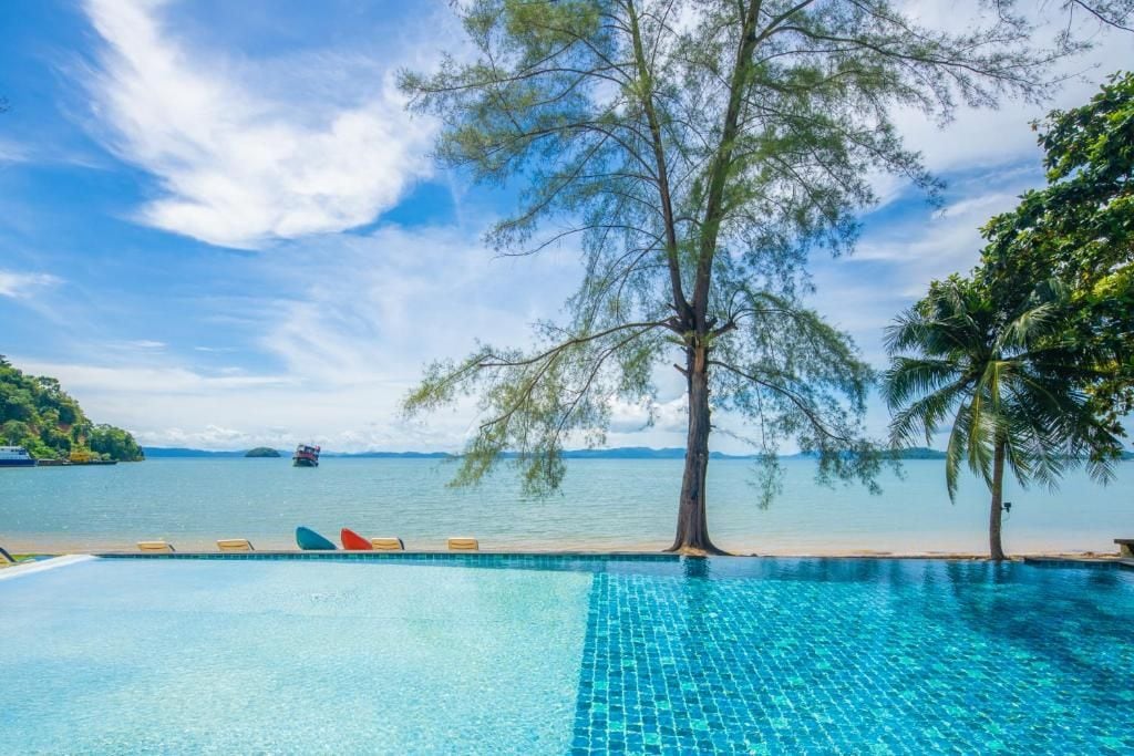 Una piscina blava i cristal·lina amb vista al mar i un arbre.