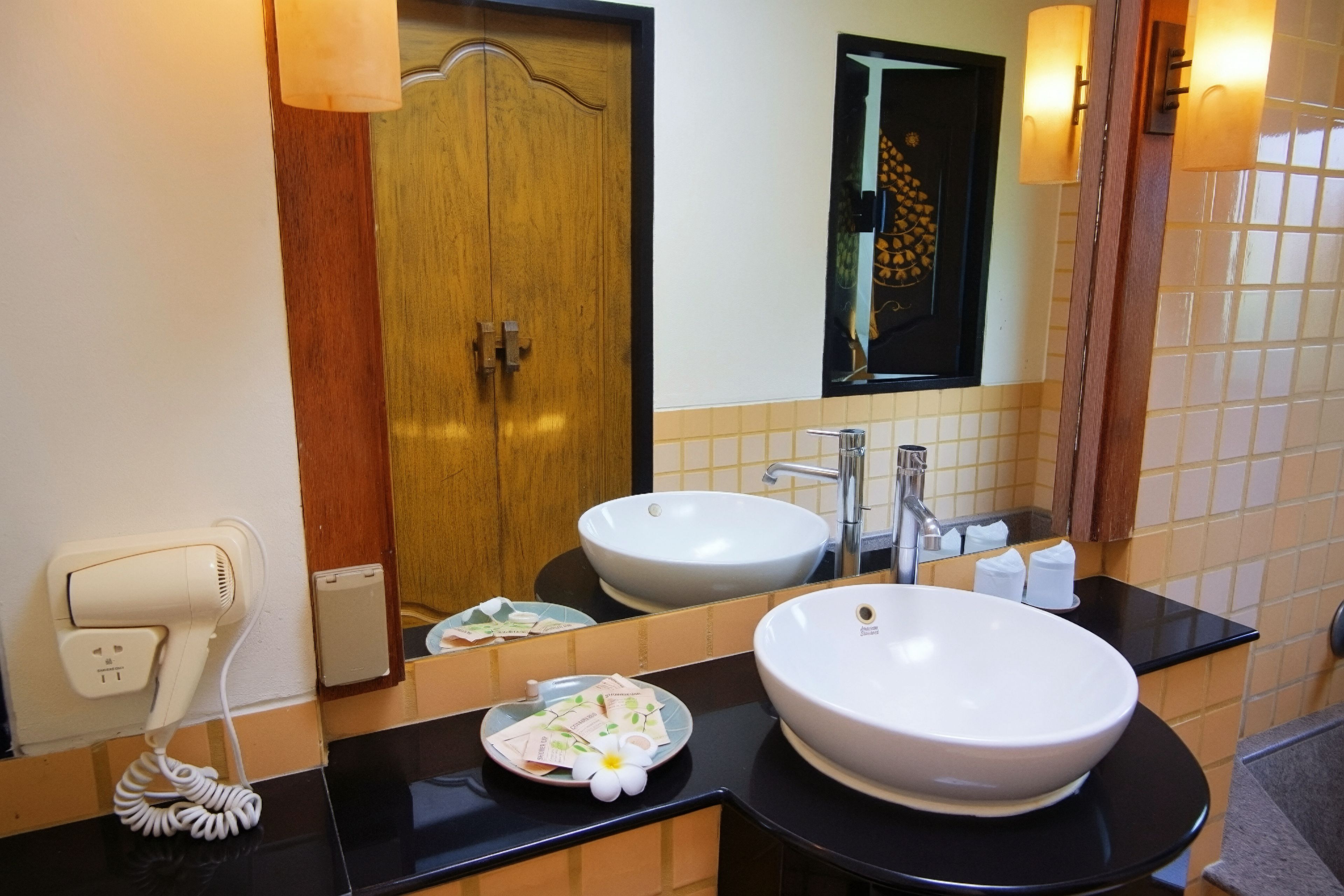 A bathroom with two sinks, a mirror, a towel dispenser, and a hairdryer.