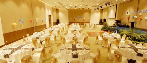 A banquet hall with round tables set for a formal event, featuring a consistent layout and a stage area.