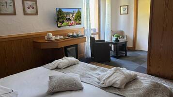 Une chambre d’hôtel avec un lit, un bureau avec une télévision, une chaise, une petite table et une porte.