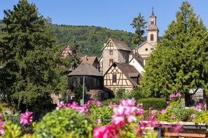 Een pittoresk Europees dorp met een kerk, stenen gebouwen en weelderige begroeiing.