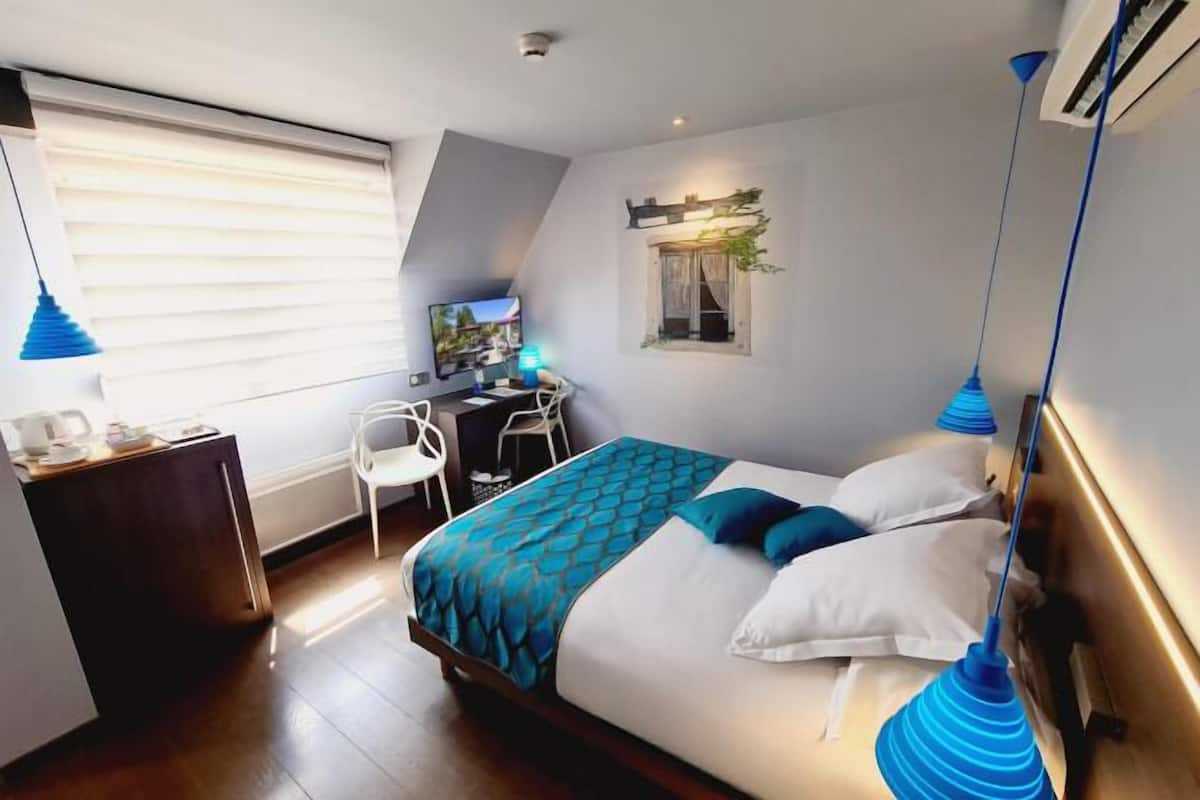 Ein Schlafzimmer mit Bett, Schreibtisch, Stuhl und einem Fenster mit Jalousien.