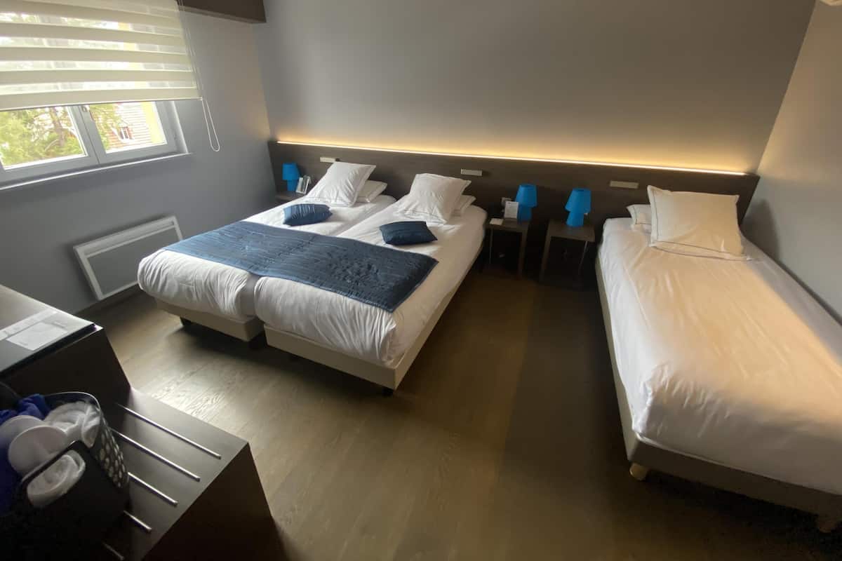 Ein Hotelzimmer mit zwei Betten, einem Schreibtisch und einem Fenster mit Jalousien.