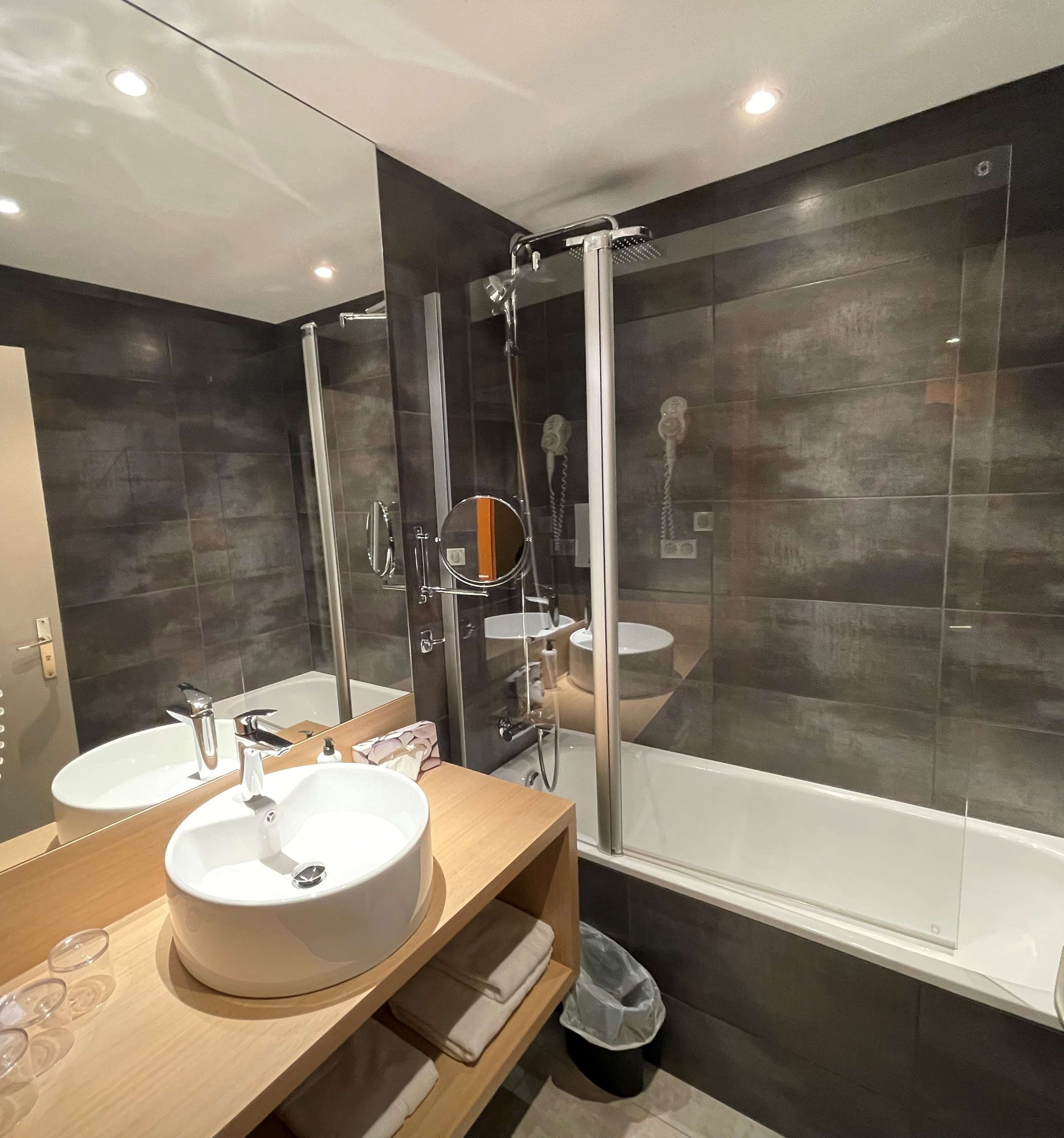 A modern bathroom with two sinks, a glass shower enclosure, and a bathtub.