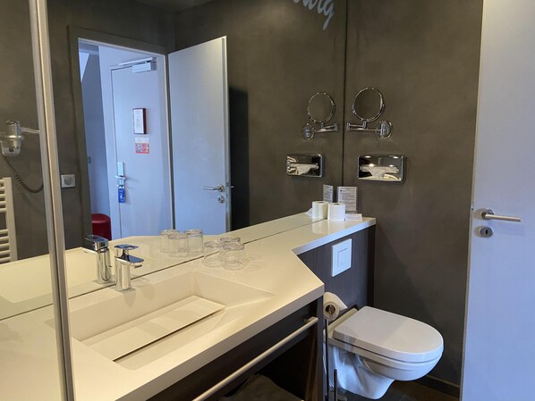 A bathroom with a white sink, a mirror, a toilet, and a towel rack.