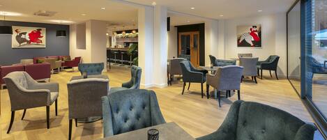 Eine moderne Hotelhalle mit Sitzbereichen, einer Bar und Kunstwerken an den Wänden.