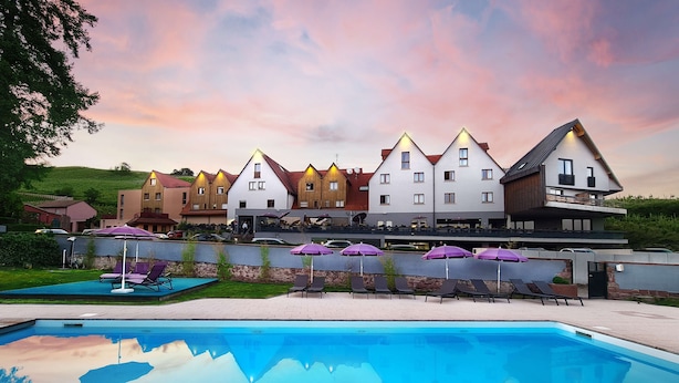 A hotel with a swimming pool, outdoor seating, and a reflection of the sky. - Best Western Plus Hotel & SPA Le Schoenenbourg (Riquewihr)