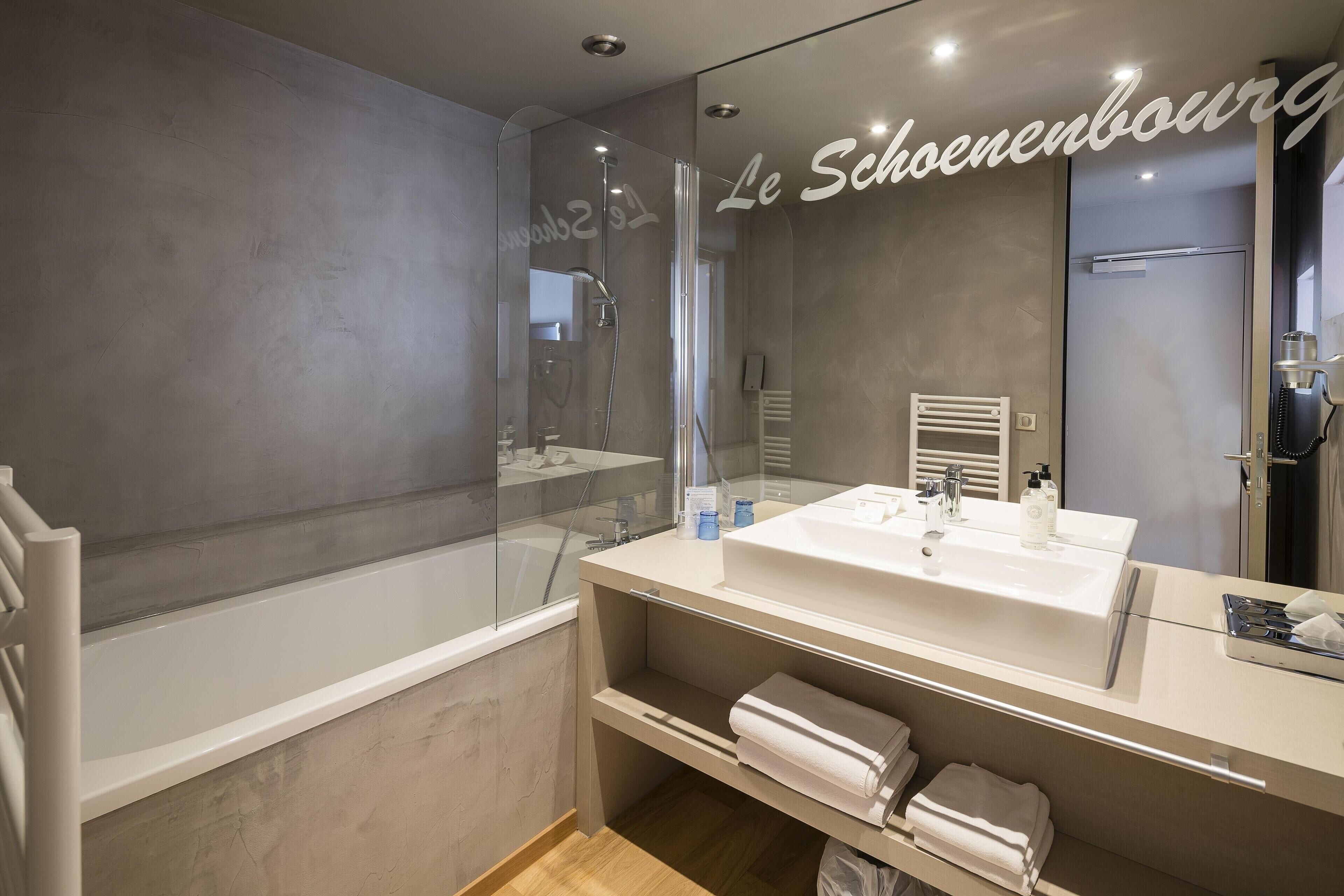 Une salle de bain moderne avec une douche à parois de verre, un grand miroir et un lavabo blanc.