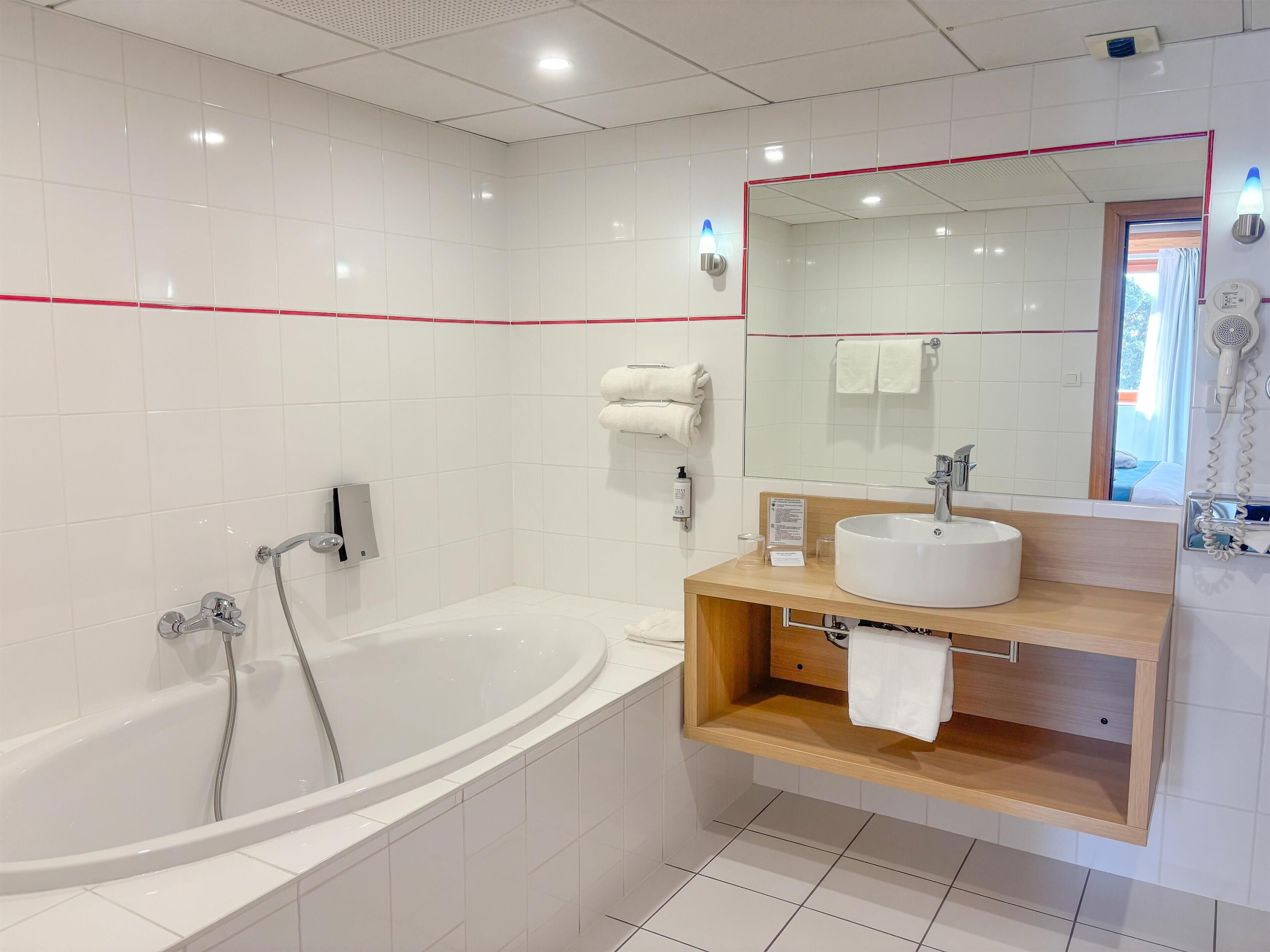 A modern bathroom with a freestanding bathtub, a vanity with a sink, a mirror, and a towel rack.
